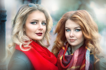 Pair portrait of a girl blonde and redhead girls with bright makeup closeup outdoor