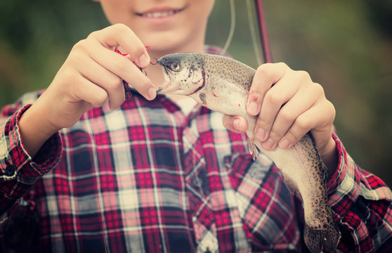 teenager boy holding catch fish on hook  .