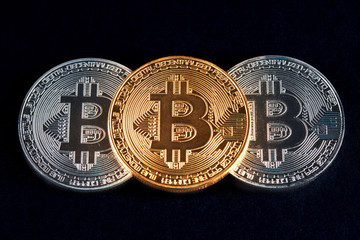 Three bitcoins golden and silver glowing on black background closeup