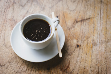 Black coffee in a white cup on the wooden table