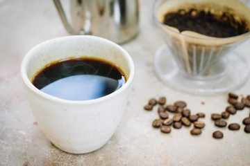 A coffee cup with roasted coffee beans and drip coffee kits.