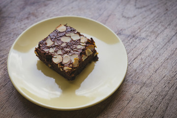 Chocolate brownie in plate on wooden table.