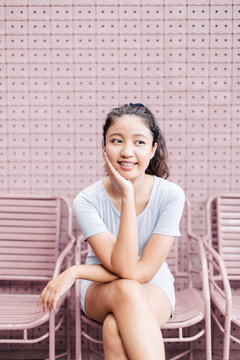 Asian young woman sitting outdoor on the pink chair