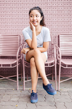 Beautiful young Asian woman sitting on the pink chair