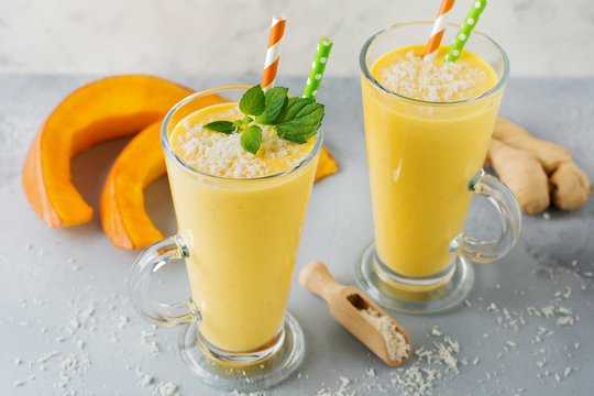 Pumpkin smoothies with ginger and coconut shavings and mint in a glass on light stone or concrete background. Healthy and delicious drink for breakfast. Selective focus. Top view. Copy space.