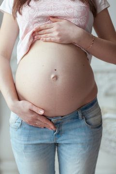 Pregnant woman seven month in jeans. Front view closeup