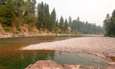 Suspension Plank and Wire Bridge over the Flathead River at the Spotted Bear Ranger Station / Campground in the Bob Marshall Wilderness area during the 2017 fall fires in Montana United States