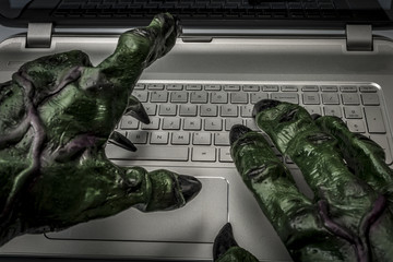 Cyber bullying, online fraud, computer virus or internet trolls concept with the hands of a troll typing on the keyboard of a laptop computer - obrazy, fototapety, plakaty