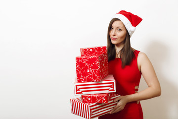 Beautiful caucasian young upset frustrated and sad woman dressed in red dress and Christmas hat holding gift boxes on white background. Santa girl with present isolated. New Year holiday 2018 concept