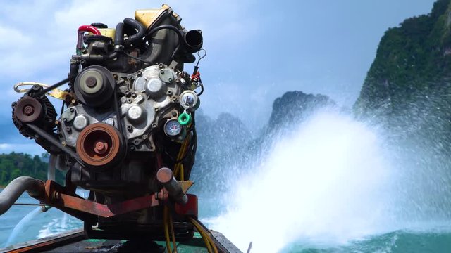 A close-up of a motor engine on a thai longtail boat and a spray from its propeller. Cheow Lan lake. Khao Sok National Park. Thailand.