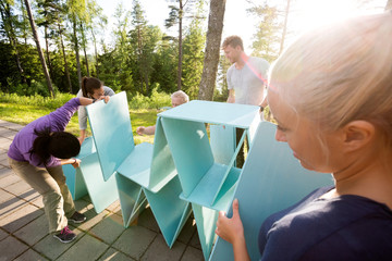 Woman Looking At Friends Making Pyramid Of Wooden Planks