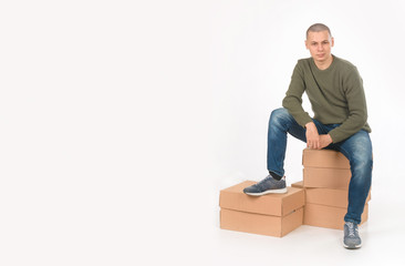 A young man is a skinhead in a green military style sweater. Studio. the guy sits on the boxes