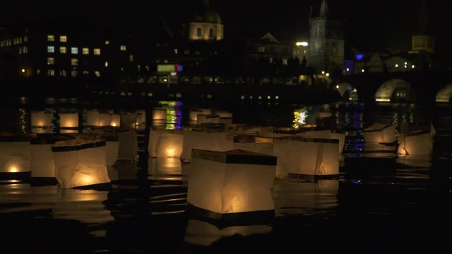 The light of paper lanterns floating on the water of Vltava illuminating the dark of Prague