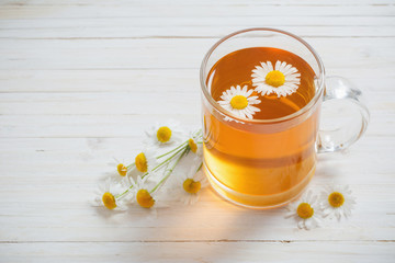 cup of tea with chamomile on white wooden background