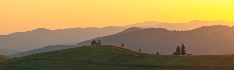 Wide panorama. Rural mountain landscape hills in scenic sunset light.