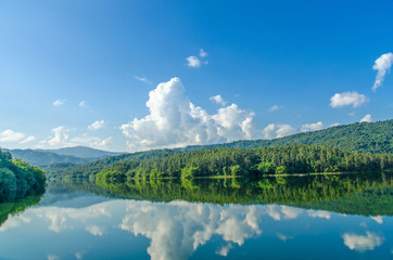 Obraz na płótnie Canvas Landscape of the dam and lake on the mountain with tree and forest and the rock with beautiful blue sky and clouds on sunshine day.