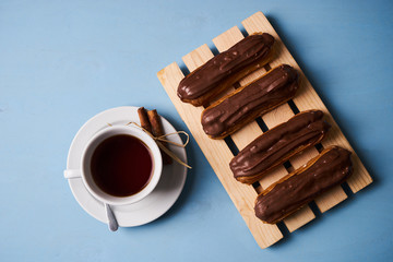 Cup of hot tea with cinnamon steak and french chocolate eclairs