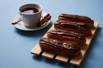 Cup of hot tea with cinnamon steak and french chocolate eclairs