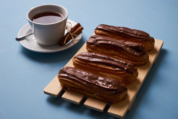 Cup of hot tea with cinnamon steak and french chocolate eclairs