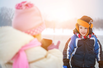 Little boy and girl playing in winter park.