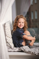 Fototapeta premium little girl on the windowsill at home