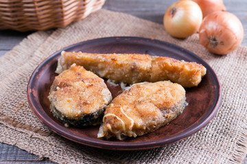 Pieces of fried fish on a plate on a wooden table