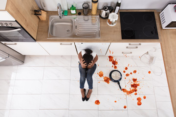 Woman Sitting On Kitchen Floor With Spilled Food