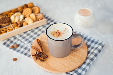 Cup of hot cappuccino with milk foam and different types of biscuits