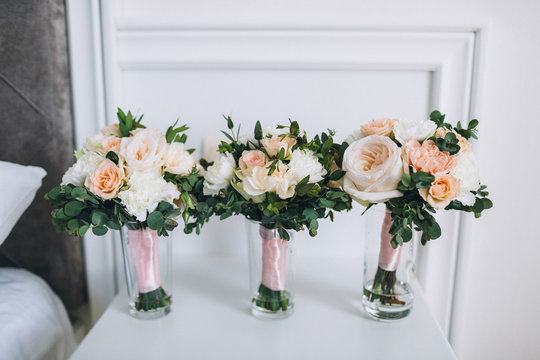 Three wedding bouquets of pink flowers stand on white table