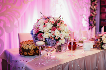 Rich garland of white roses and pink hydrangeas lies on the pink dinner table