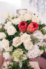 Centerpiece made of stunning white roses stands on a little square dinner table