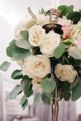 Centerpiece made of stunning white roses stands on a little square dinner table