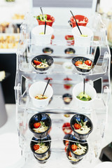 Circle with different cold salads in cups put on a candy bar