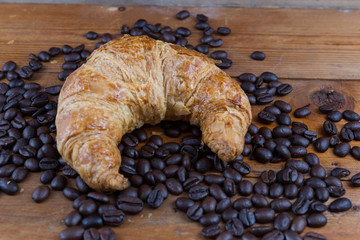 croissant and coffee beans on wooden table