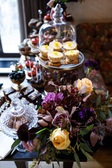 Dishes with cookies, eclairs, macaroons and other sweets made of chocolate and cream served on black table