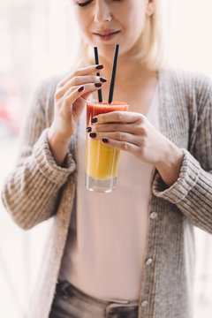 Blonde woman holding a colorful drink