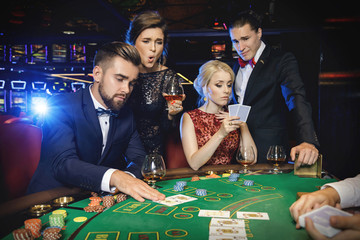 Group of rich people is playing poker in the casino - obrazy, fototapety, plakaty