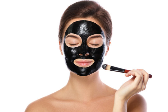 Beautiful woman is applying purifying black mask on her face