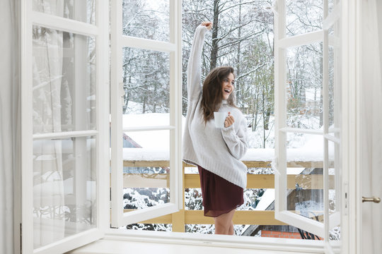 Happy woman with a cup of hot drink on the balcony at winter day
