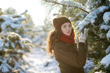 Pretty young woman in hat and coat play in snow winter park