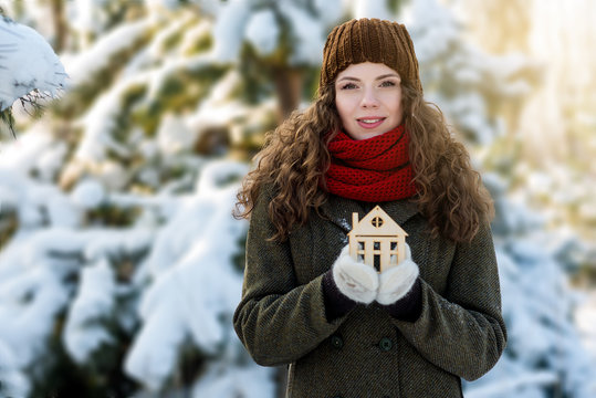 Woman holds wooden toy house in her hands. Energy and warm save concept