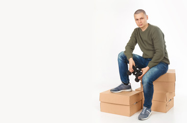 A young man is a skinhead in a green military style sweater with binoculars. Studio