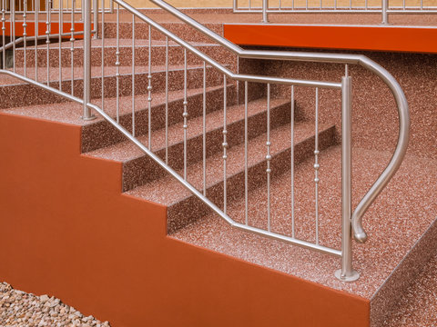 Modernes Treppengel&auml;nder aus Edelstahl an Au&szlig;entreppe mit Steinteppich in rotbraun - Modern stainless steel railing on outside staircase with stone carpet in red-brown