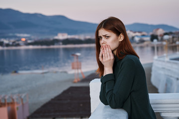 Young beautiful woman outdoors by the sea in a sweater, sadness