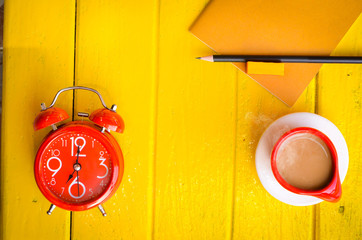 Good morning word,Retro Clock with cup and stationery of coffee on yellow background,empty space