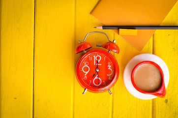 Good morning word,Retro Clock with cup and stationery of coffee on yellow background,empty space