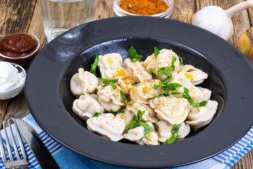 Plate with boiled dumplings on wooden table