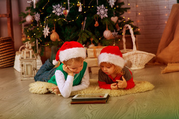 kids choose Christmas presents on touch pad in decorated living room