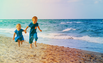 little boy and girl run play at beach