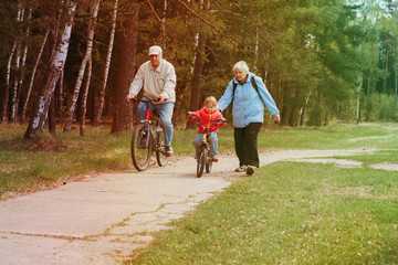 active grandparents teaching granddaughter to ride bike